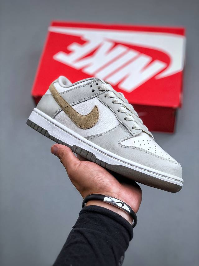 Nike Sb Dunk Low 灰棕鞋身整体以浅灰与白色皮革为底，搭配米白色框架呈现，营造出独特的复古气息。此外侧面的swoosh采用棕色反毛皮革，营造出丰富